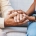 Two people hold hands in a comforting gesture: an older adult's hands resting on a younger caregiver's hands wearing a blue uniform.—care and support scene